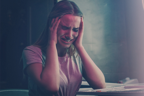 Девушка плачет, держась за голову